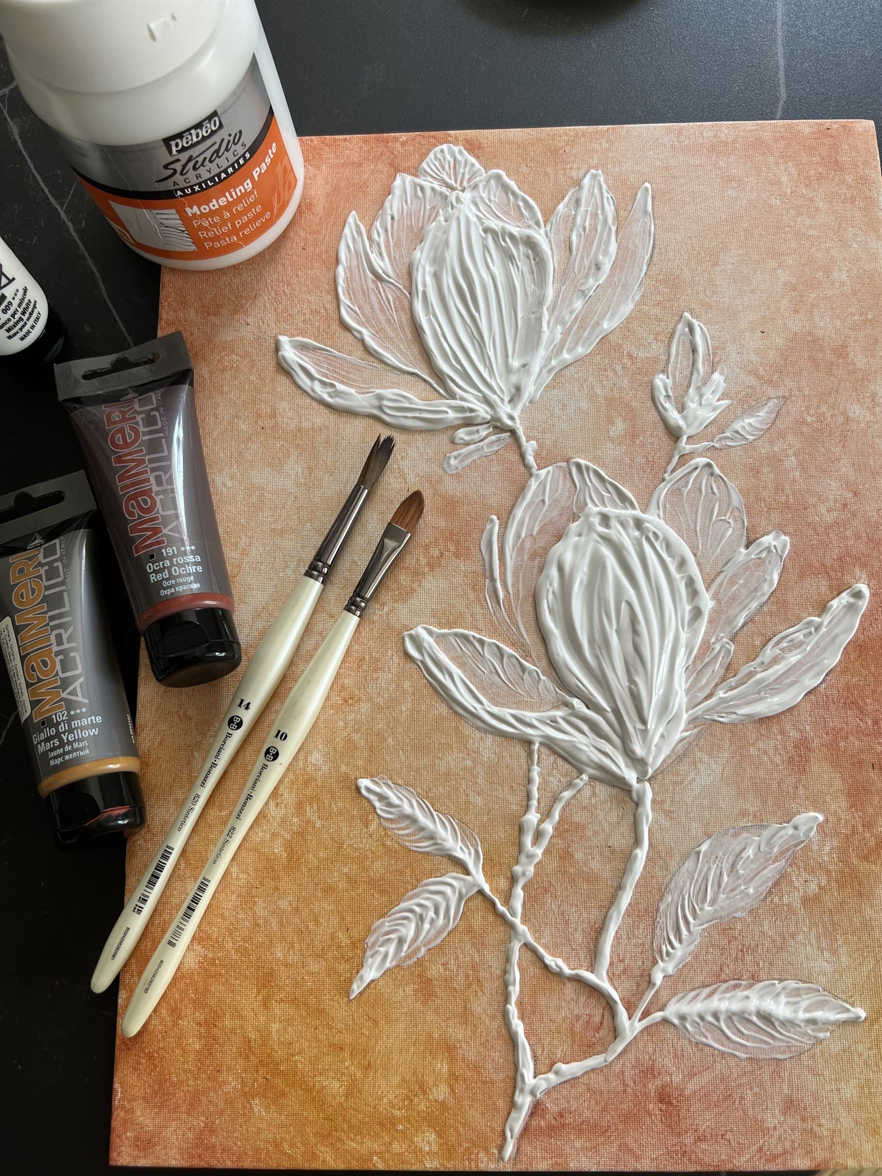 Fiori materici in rilievo sulla tela con pennelli, colori e pasta modellante